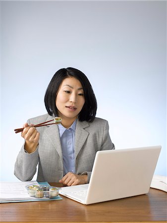 simsearch:614-02681101,k - Businesswoman eating and working at desk Photographie de stock - Premium Libres de Droits, Code: 6122-07702993