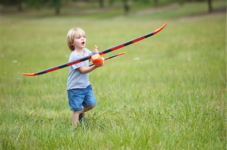 Boy playing with toy airplane outdoors Photographie de stock - Premium Libres de Droits, Code: 6122-07703041