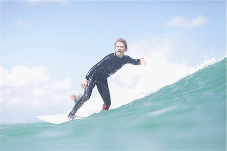 roupa molhada - Teenage surfer riding a wave Foto de stock - Royalty Free Premium, Número: 6122-07703169