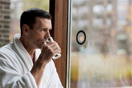 simsearch:6122-07703397,k - Man in bathrobe drinking water by window Stockbilder - Premium RF Lizenzfrei, Bildnummer: 6122-07703399