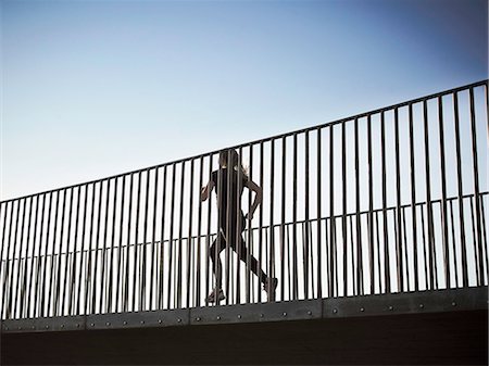 simsearch:632-06118707,k - Woman running on skybridge Photographie de stock - Premium Libres de Droits, Code: 6122-07703832