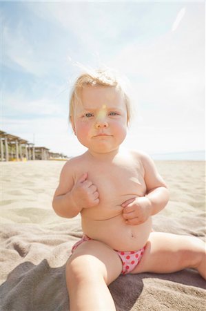 Frowning baby sitting on towel on beach Stock Photo - Premium Royalty-Free, Code: 6122-07704150