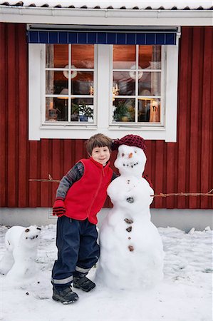 Smiling boy standing with snowman Stock Photo - Premium Royalty-Free, Code: 6122-07704248