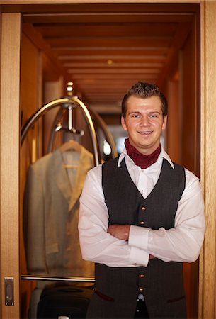 Bellhop smiling with luggage Stock Photo - Premium Royalty-Free, Code: 6122-07704479