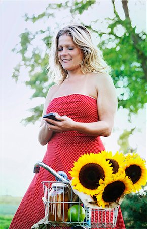 Woman using cell phone on bicycle Stock Photo - Premium Royalty-Free, Code: 6122-07704880