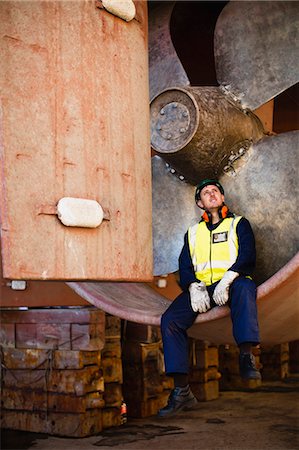 Worker sitting in propeller on dry dock Foto de stock - Royalty Free Premium, Número: 6122-07705070