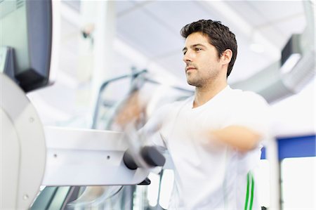 simsearch:649-05950199,k - Man using exercise machine in gym Stock Photo - Premium Royalty-Free, Code: 6122-07705126