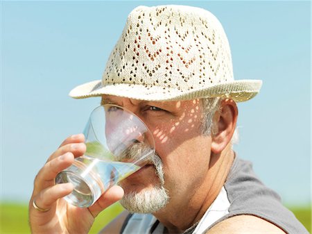 Older man drinking water outdoors Stock Photo - Premium Royalty-Free, Code: 6122-07705277