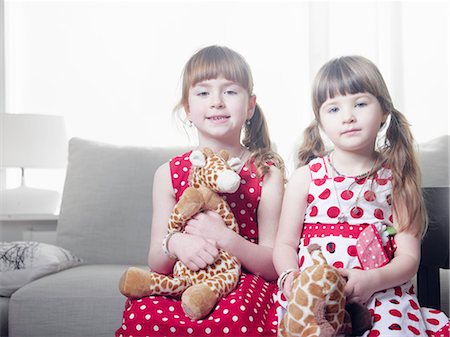 Girls holding stuffed animals on sofa Stock Photo - Premium Royalty-Free, Code: 6122-07705327