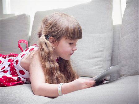 Girl using tablet computer on sofa Photographie de stock - Premium Libres de Droits, Code: 6122-07705331