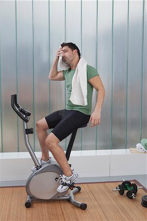 Man wiping sweat on exercise machine Stock Photo - Premium Royalty-Free, Code: 6122-07705556