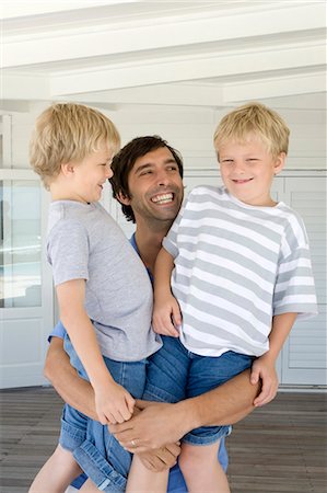 father posing with son - Smiling father holding sons Stock Photo - Premium Royalty-Free, Code: 6122-07705578