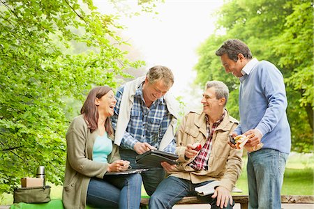 Friends using tablet computer in park Stock Photo - Premium Royalty-Free, Code: 6122-07705616