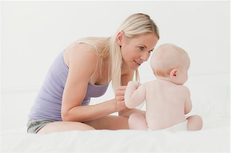 diapering mother to baby - Mother playing with baby on bed Stock Photo - Premium Royalty-Free, Code: 6122-07705799