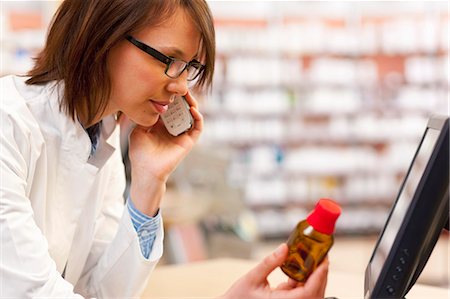 pharmacist helping - Pharmacist talking on phone at counter Stock Photo - Premium Royalty-Free, Code: 6122-07705877