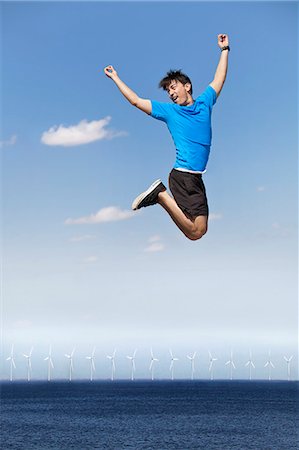 simsearch:6122-07695082,k - Man jumping for joy over wind turbines Stock Photo - Premium Royalty-Free, Code: 6122-07705916