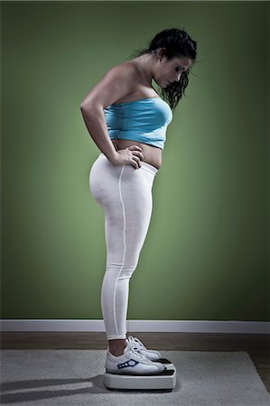 sovrappeso - Woman weighing herself on scale Fotografie stock - Premium Royalty-Free, Codice: 6122-07706087