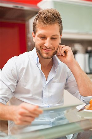 simsearch:6122-07705331,k - Smiling man reading at table Stock Photo - Premium Royalty-Free, Code: 6122-07706145