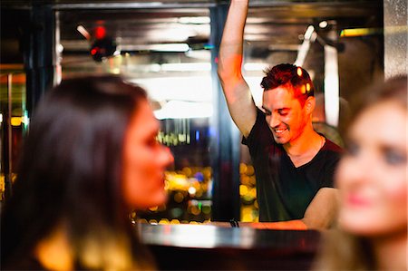 people dancing in night club with arms in air - Bartender waving to customers in bar Stock Photo - Premium Royalty-Free, Code: 6122-07706168