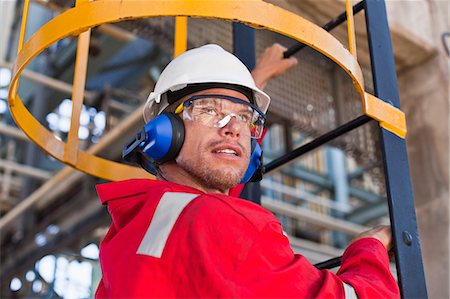 Worker climbing ladder at oil refinery Stockbilder - Premium RF Lizenzfrei, Bildnummer: 6122-07706278