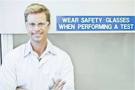 responsible technician - Scientist wearing goggles by safety sign Photographie de stock - Premium Libres de Droits, Code: 6122-07706300