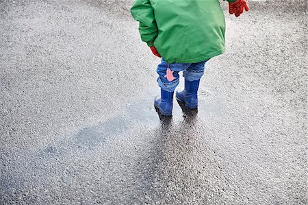 Boy in rain boots playing in puddle Foto de stock - Sin royalties Premium, Código: 6122-07706437