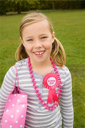 pigtail with pink ribbons - Smiling girl holding birthday present Stock Photo - Premium Royalty-Free, Code: 6122-07706556