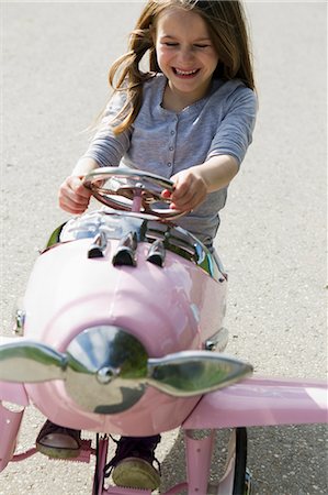 simsearch:6122-07696599,k - Smiling girl driving toy airplane Photographie de stock - Premium Libres de Droits, Code: 6122-07706672