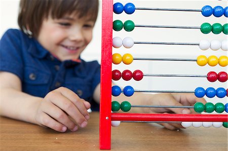 Smiling boy playing with abacus Stock Photo - Premium Royalty-Free, Code: 6122-07706675