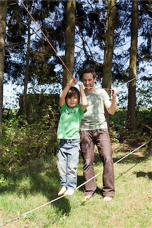 simsearch:649-03770647,k - Father helping son walk on tight rope Photographie de stock - Premium Libres de Droits, Code: 6122-07706678