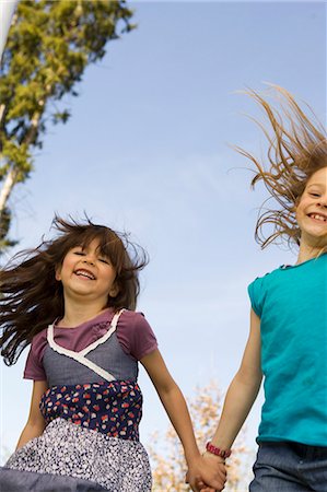 Smiling girls holding hands outdoors Stock Photo - Premium Royalty-Free, Code: 6122-07706685