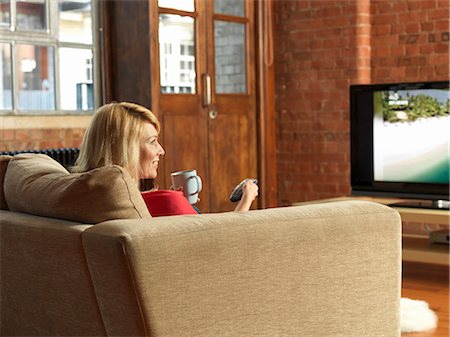 Woman watching television on sofa Photographie de stock - Premium Libres de Droits, Code: 6122-07706714