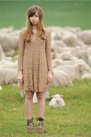 simsearch:6122-07697627,k - Teenage girl standing in field of sheep Stock Photo - Premium Royalty-Free, Code: 6122-07707389