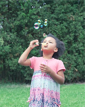 Girl blowing bubbles outdoors Photographie de stock - Premium Libres de Droits, Code: 6122-07707474