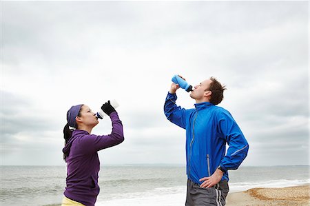 Couple drinking after exercise on beach Stock Photo - Premium Royalty-Free, Code: 6122-08211848
