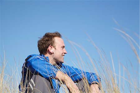 simsearch:6122-08211851,k - Young man sitting relaxing in long grass Fotografie stock - Premium Royalty-Free, Codice: 6122-08211852