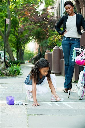 Mother watching daughter draw on sidewalk Photographie de stock - Premium Libres de Droits, Code: 6122-08212550