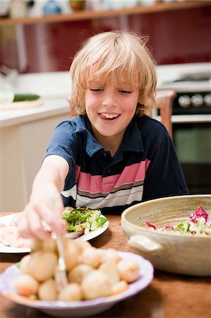 Young boy at the family dinner table helping himself to potatoes Foto de stock - Sin royalties Premium, Código: 6122-08212652