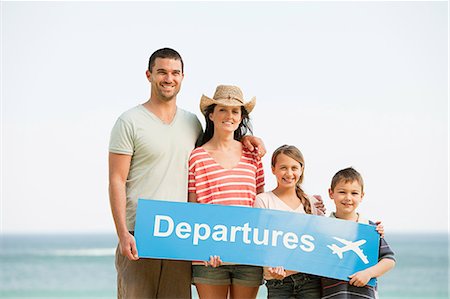 simsearch:632-01156525,k - Family holding an airport departures sign on a beach Photographie de stock - Premium Libres de Droits, Code: 6122-08212668