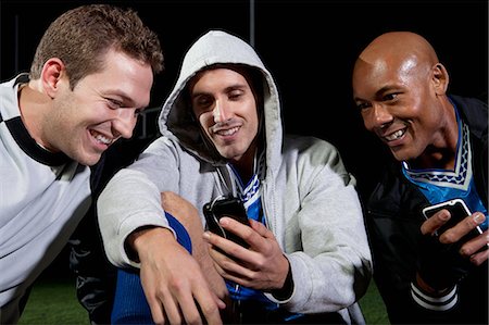 simsearch:6122-07697777,k - Soccer players looking at cellphone on pitch Photographie de stock - Premium Libres de Droits, Code: 6122-08212777