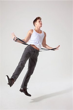 simsearch:649-06041684,k - Young man in mid air pulling trouser braces Stock Photo - Premium Royalty-Free, Code: 6122-08212733