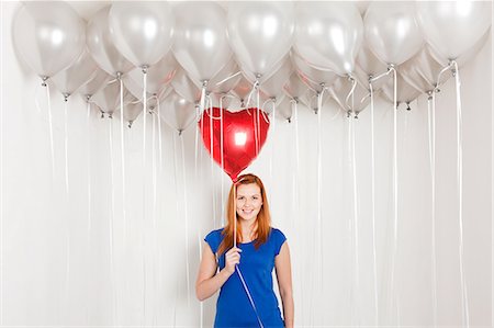 picture of a women with helium balloons - Young woman holding heart shaped balloon Stock Photo - Premium Royalty-Free, Code: 6122-08212846