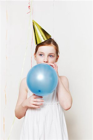 simsearch:6122-08212873,k - Girl in party hat, blowing up balloon Stock Photo - Premium Royalty-Free, Code: 6122-08212873