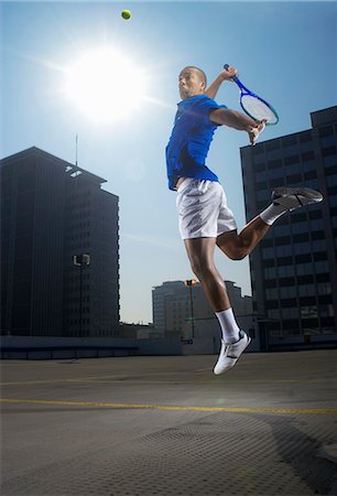 simsearch:6113-06909280,k - Tennis player jumping on rooftop court Stock Photo - Premium Royalty-Free, Code: 6122-08229091