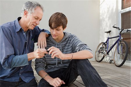 parent and teen bikes - Father and son examining tool together Stock Photo - Premium Royalty-Free, Code: 6122-08229118