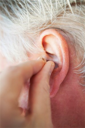 simsearch:400-07055447,k - Older person inserting hearing aid Photographie de stock - Premium Libres de Droits, Code: 6122-08229441