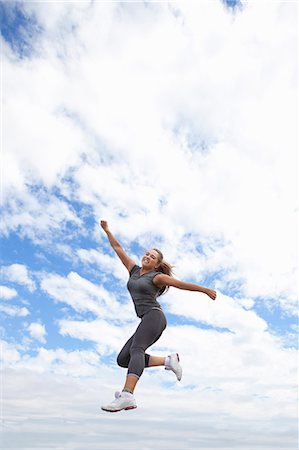 simsearch:6122-08229659,k - Runner jumping for joy outdoors Foto de stock - Royalty Free Premium, Número: 6122-08229662