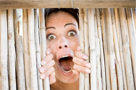 erstaunlich - Close up of woman gasping behind fence Stockbilder - Premium RF Lizenzfrei, Bildnummer: 6122-08229695