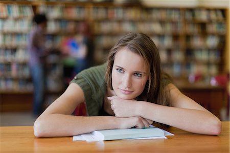 Student resting chin on books in library Stock Photo - Premium Royalty-Free, Code: 6122-08229604