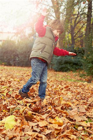 sweater vest - Boy playing in autumn leaves Stock Photo - Premium Royalty-Free, Code: 6122-08229764